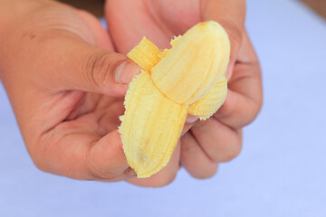 Hand Holding Freshly Peeled Banana with Natural Background for Healthy Organic Snack Concept