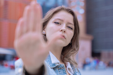 Serious young woman raising her hand in a stop gesture, expressing determination and...