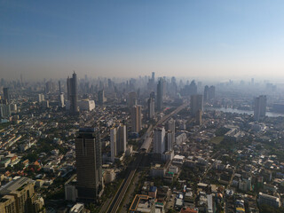 Fototapeta premium Aerial view of Bangkok city with skytrain railway and skyscrapers in morning haze