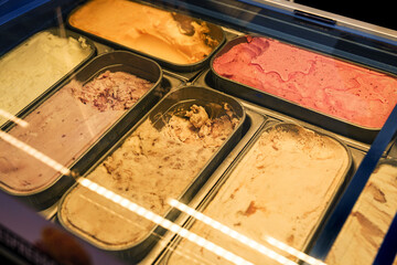 Variety of colorful gelato flavors displayed in a glass case at a dessert shop
