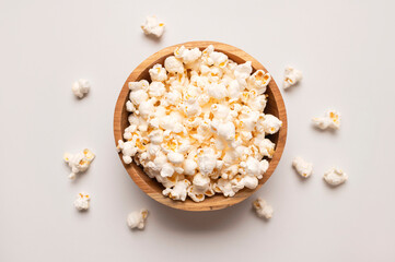 White salty or sweet popcorn in wooden bowl on light gray background, top view flat lay. Corn flakes, food for movie or cinema. Delicious appetizer, party snack. Empty space for text