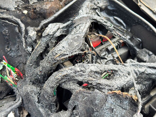 Burned car fuse box and wiring with melted insulation, scorched plastic housing, and exposed...