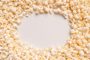 Scattered salty or sweet popcorn on light gray background top view. Corn flakes, food for movie or cinema. Delicious appetizer, party snack. Empty space for text, advertising