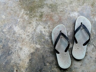 Worn flip-flops resting on weathered concrete.