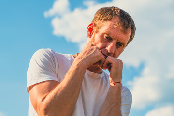 A man wearing a white shirt is practicing his boxing techniques in a picturesque park with lush...