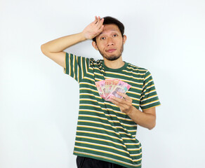 Man Holding Money Showing Uncertain Expression About Financial Situation
