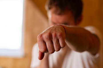 A man is standing in a boxing stance, with a serious expression. He appears ready for action, demonstrating assertiveness and determination.