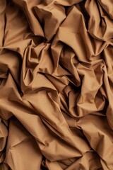 Obraz premium A close-up view of wrinkled, textured fabric in a warm brown hue, showcasing intricate folds and creases.