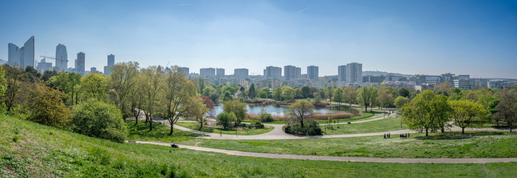 Nanterre, France - 04 11 2025: Andre Malraux Park. Panoramic aerial view of the pond, trees in leaf, reeds and La Defense towers in back.