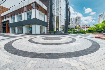 Empty circular brick plaza in front of modern commercial building exterior architecture.