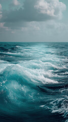 Fototapeta premium The mesmerizing turquoise ocean glistens under a cloudy sky, its restless waves creating a stunning display of power and beauty, captivating all who witness it.