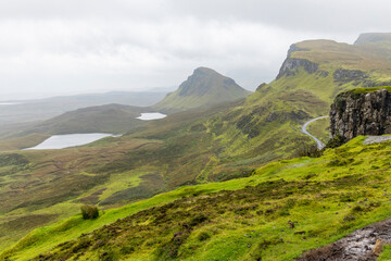 Obraz premium The Quiraing, Isle of Skye lush green landscapes, pure air, dramatic cliffs. A surreal trail through wild nature, perfect for trekking, silence, breathing untouched beauty, mystical rock formations.