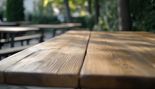 Long wooden table in an outdoor beer garden with blurred tables and benches, close-up. A blank template for a restaurant