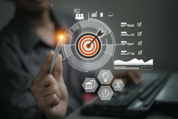 A hand holds a stylus pointed at a digital target surrounded by charts, checklists, and business icons, symbolizing focus and analytics..