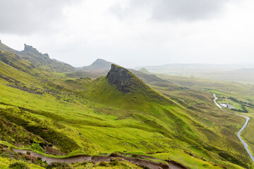 Fototapeta premium The Quiraing, Isle of Skye lush green landscapes, pure air, dramatic cliffs. A surreal trail through wild nature, perfect for trekking, silence, breathing untouched beauty, mystical rock formations.