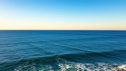 Naklejka premium Serene ocean view, vast expanse of blue water meeting a clear sky at sunset