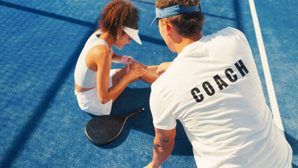 Woman, sport and knee injury with coach for pain, medical assistance or help on outdoor court....