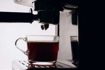 Espresso machine brewing coffee in a glass cup with dark background showcasing rich beverage and steam rising for coffee lovers and enthusiasts concept