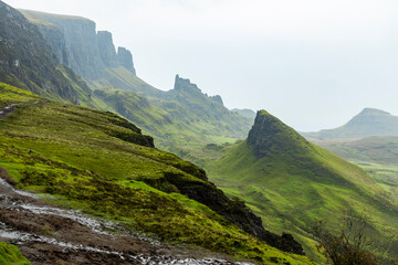 Obraz premium The Quiraing, Isle of Skye lush green landscapes, pure air, dramatic cliffs. A surreal trail through wild nature, perfect for trekking, silence, breathing untouched beauty, mystical rock formations.