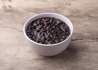 Cooked black beans in a bowl over wooden table