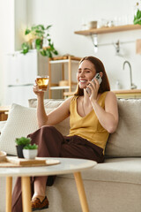 Cheerful woman chatting with a friend while sipping a drink in her cozy living room
