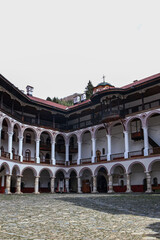 Scenic view of the Rila Monastery of St. John in Bulgaria, surrounded by lush forest and majestic mountains. A historic Orthodox landmark and spiritual center nestled in natural beauty.