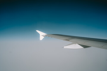 Commercial airplane wing, flying over cloudy weather. Passenger window point of view, no people