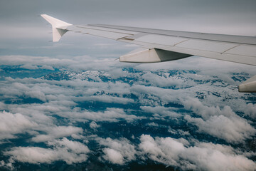 Commercial airplane wing, flying over cloudy weather. Passenger window point of view, no people