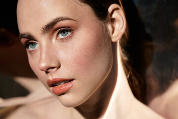 Young beautiful woman with striking blue eyes and radiant skin in artistic close up portrait