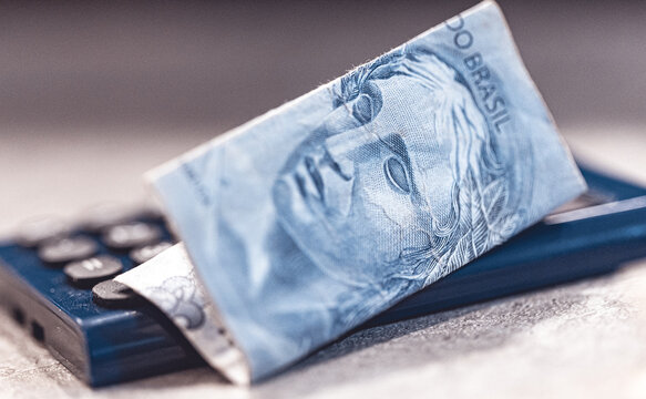 Dinheiro, Brasil, Real Brasileiro. Uma nota de 2 reais sobre uma pequena calculadora azul. Crise financeira, juros altos e infla&ccedil;&atilde;o. Economia Brasileira. 