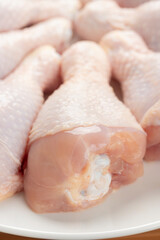 Close up of raw chicken drumsticks on white plate