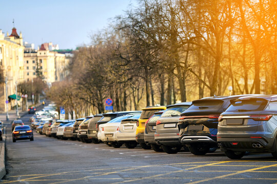 Cars parked in angled row formation in crowded city parking lot, tight urban space and vehicle congestion along the roadside in downtown. Urban traffic problem with rows of cars parked tight in a city
