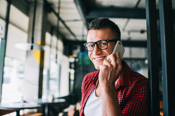 Joyful man having conversation on smartphone in cafe
