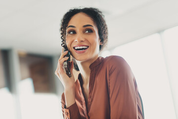 Smiling young professional woman engaged in a phone conversation in a bright, modern office environment