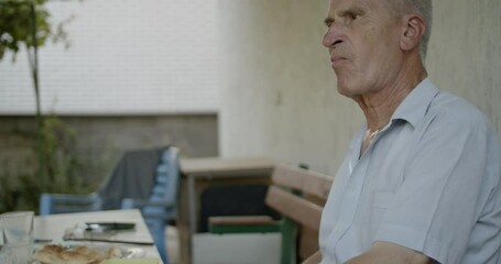 A mature man manages a runny nose during his breakfast. This evokes themes of aging, health, and everyday life.