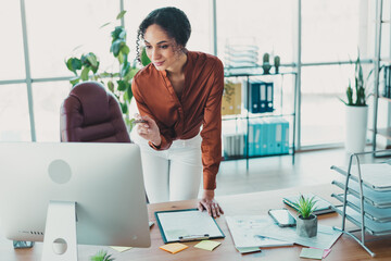 Young businesswoman working confidently in a modern office with natural daylight and organized workspace