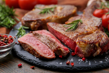 Pieces of delicious beef meat and spices on wooden table, closeup
