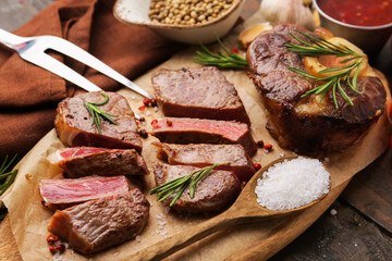Pieces of delicious beef meat with spices on wooden table, closeup