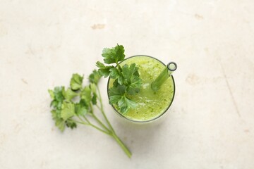 Healthy parsley smoothie in glass and leaves on light textured table, flat lay