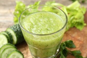 Healthy parsley smoothie in glass, leaves and cucumber on table, closeup