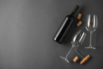 Naklejka premium Bottle of wine, corks and glasses on grey background, flat lay. Space for text