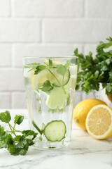 Healthy drink with parsley, cucumbers and lemons on white marble table