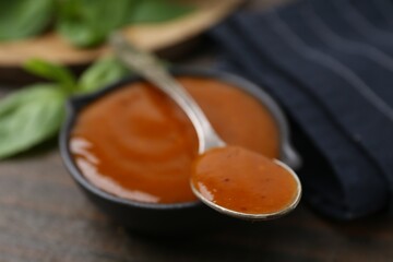 Tasty curry sauce and basil leaves on wooden table, closeup