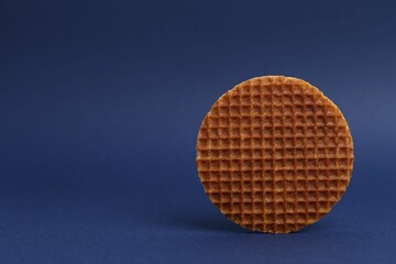 One tasty round waffle on blue background. Space for text