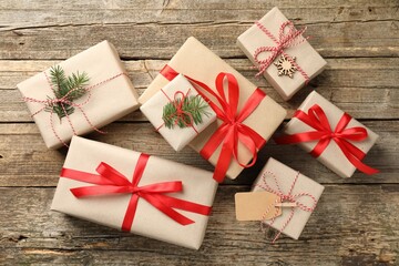 Fototapeta premium Gifts wrapped in kraft paper with fir tree branches on wooden background, flat lay