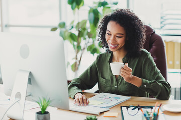 Professional businesswoman working at her desk with a coffee cup in a bright modern office