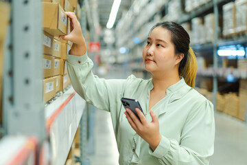 female warehouse manager checks inventory while holding smartphone, ensuring accurate shipping and...