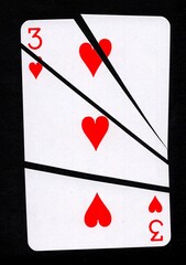 A playing card in the suit of hearts cut into sharp pieces.