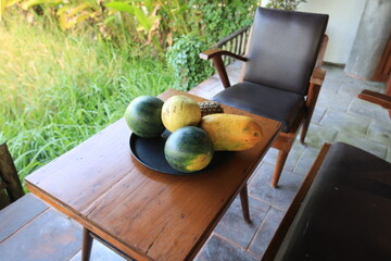 Wooden table with a variety of fruits including watermelons, bananas, and cantaloupes