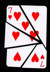 A playing card in the suit of hearts cut into sharp pieces.